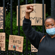 A woman raises her fist in the air as Black Lives Matter protesters hang their banners on the fence on June 7, 2020, in Edinburgh, Scotland.